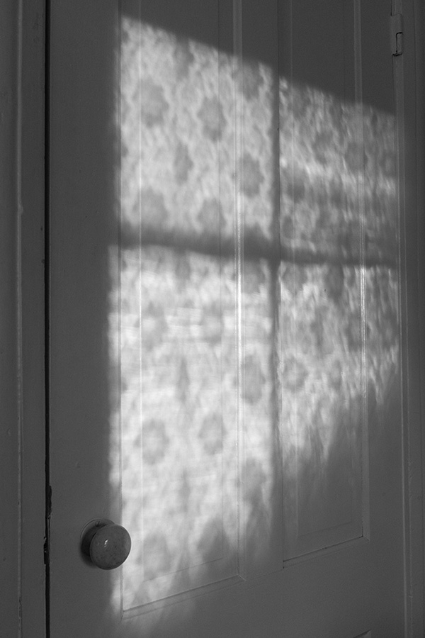 Black and White Photo of Lace Curtain Shadows on an Old Door.
